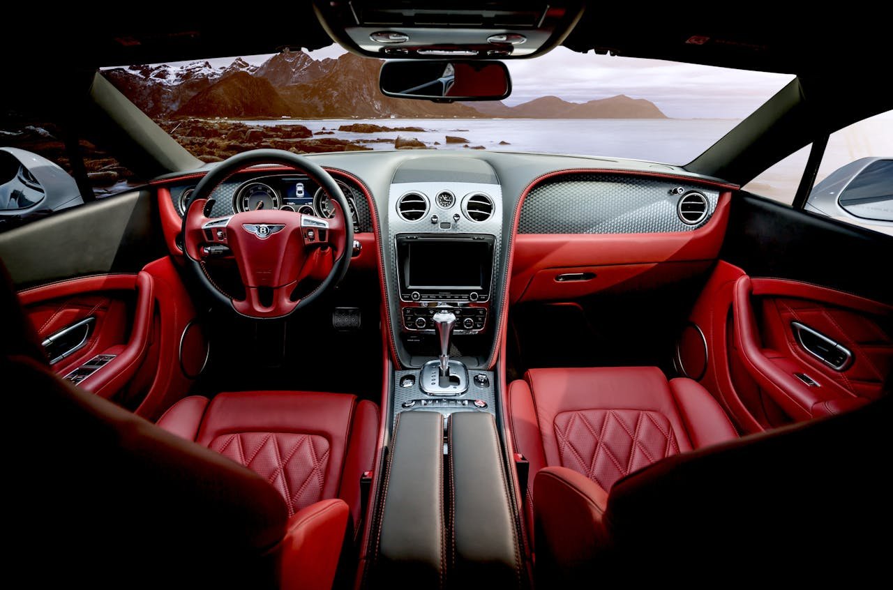 Red leather luxury sports car interior with mountain backdrop outside the window.